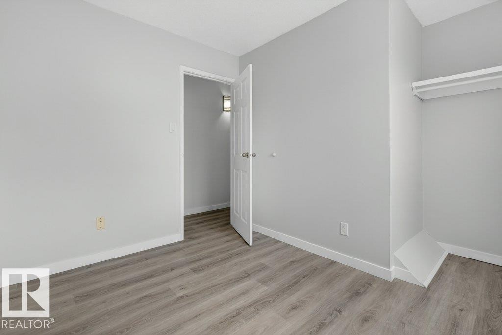 Light gray wall finishes, white trim, and wood-finish flooring - 3E Twin Terrace, Edmonton, AB - Indoor Photo Showing Other Room
