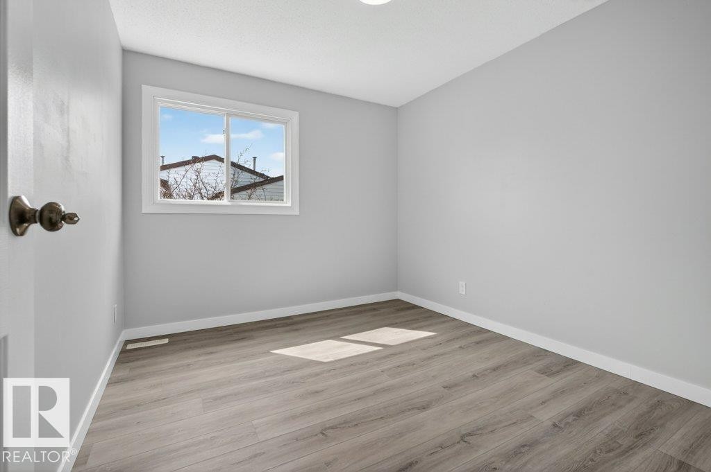 Room featuring a window with white trim, light gray walls, and wood-finish flooring - 3E Twin Terrace, Edmonton, AB - Indoor Photo Showing Other Room