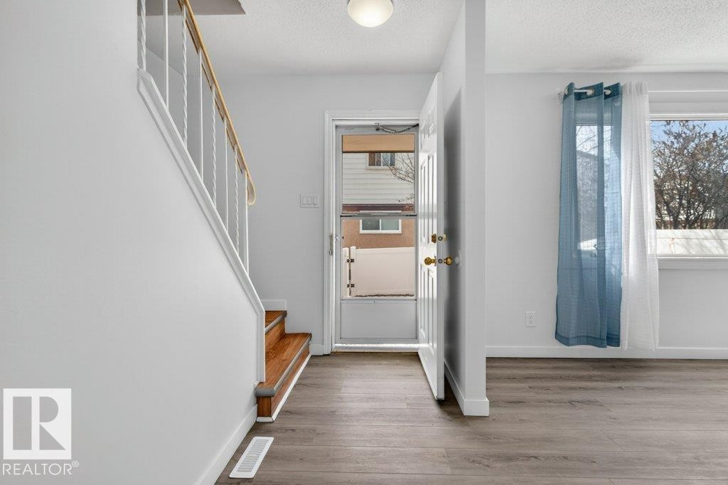 Entryway featuring wood-finish flooring, white painted walls, and a staircase with wood treads and a white railing - 3E Twin Terrace, Edmonton, AB - Indoor Photo Showing Other Room