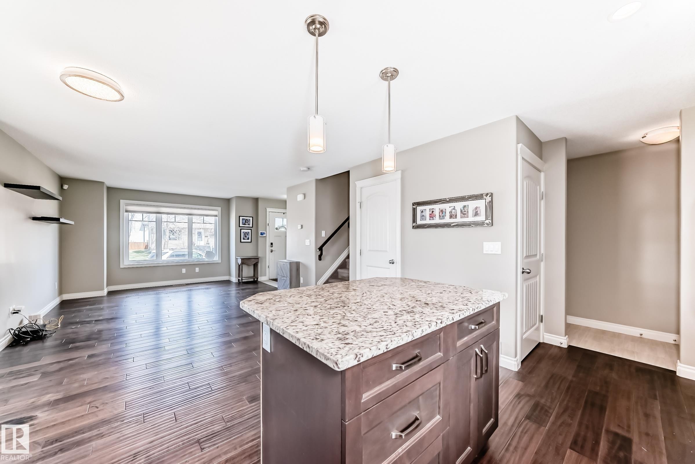 Central kitchen island with granite countertop and pendant lighting - 10519 114 Avenue, Edmonton, AB - Indoor
