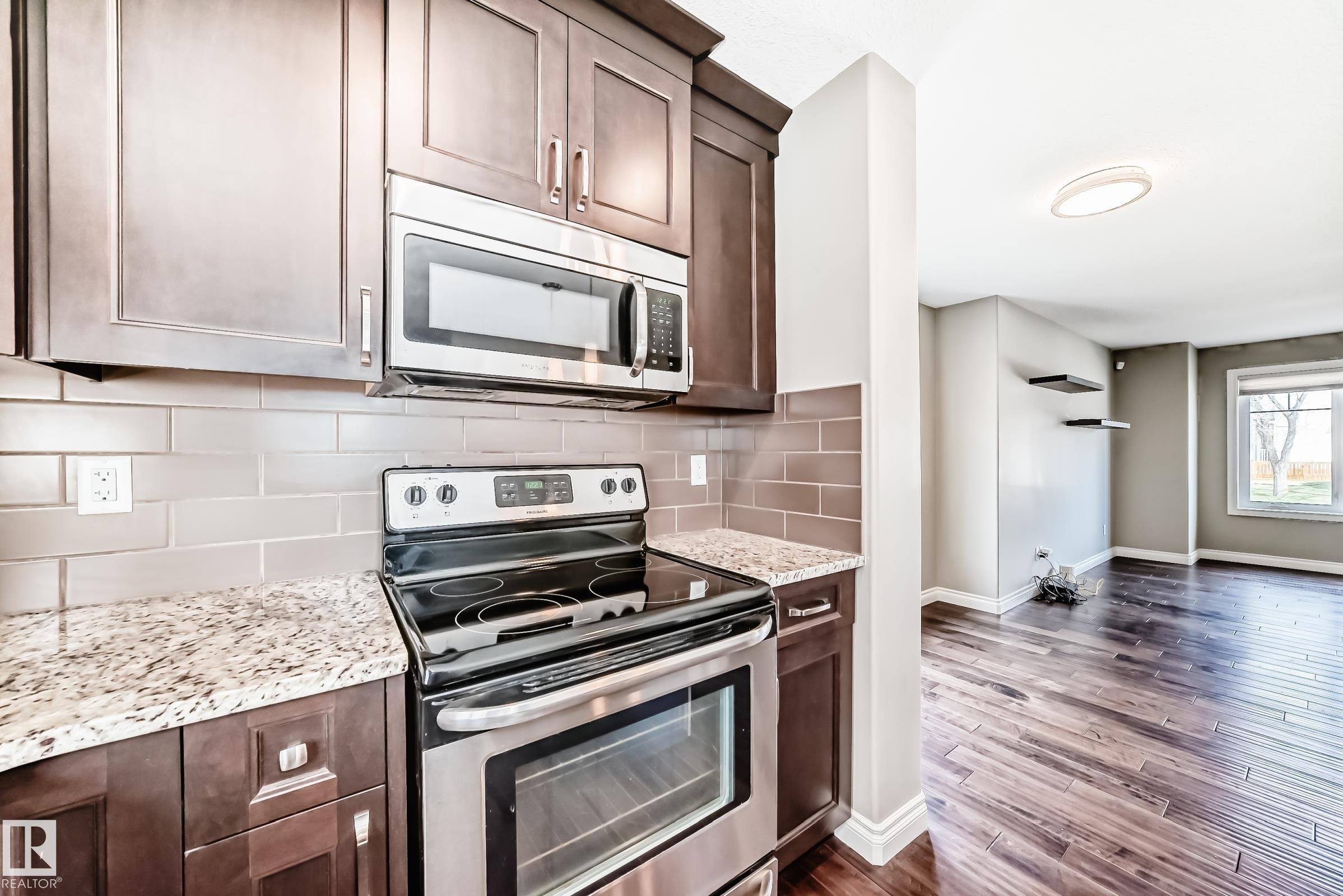 Modern kitchen featuring dark wood cabinetry, light speckled countertops, and a subway tile backsplash - 10519 114 Avenue, Edmonton, AB - Indoor Photo Showing Kitchen With Stainless Steel Kitchen With Upgraded Kitchen