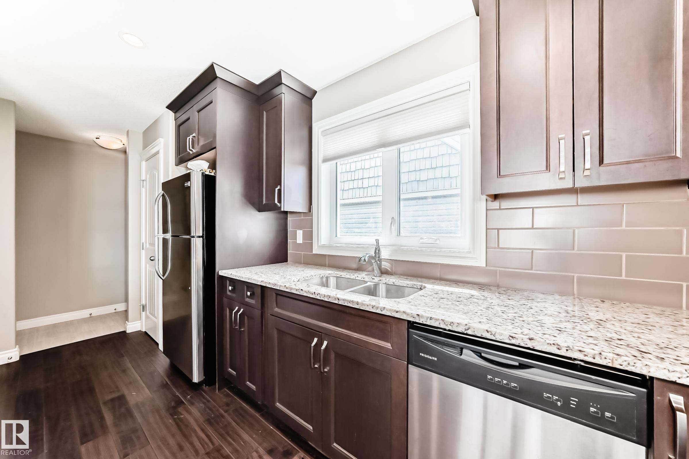 Kitchen featuring dark wood-finish cabinetry, light speckled countertops, and a subway tile backsplash - 10519 114 Avenue, Edmonton, AB - Indoor Photo Showing Kitchen With Double Sink