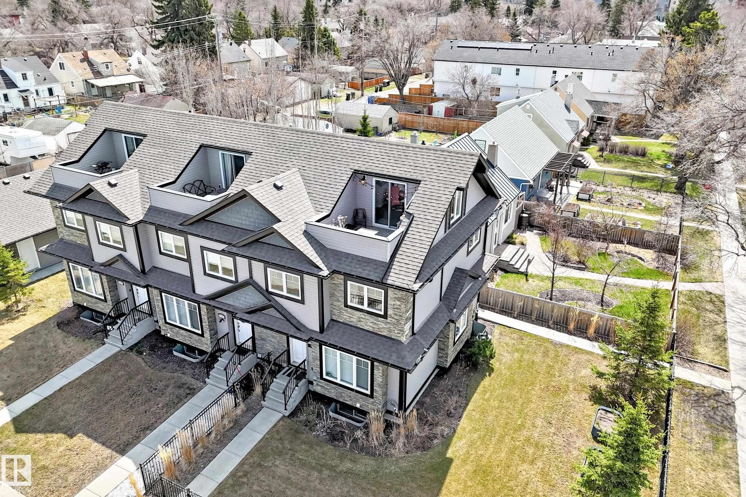 Modern townhome exterior with dormer windows, stone veneer accents, individual front entrances, and private balconies - 10519 114 Avenue, Edmonton, AB - Outdoor