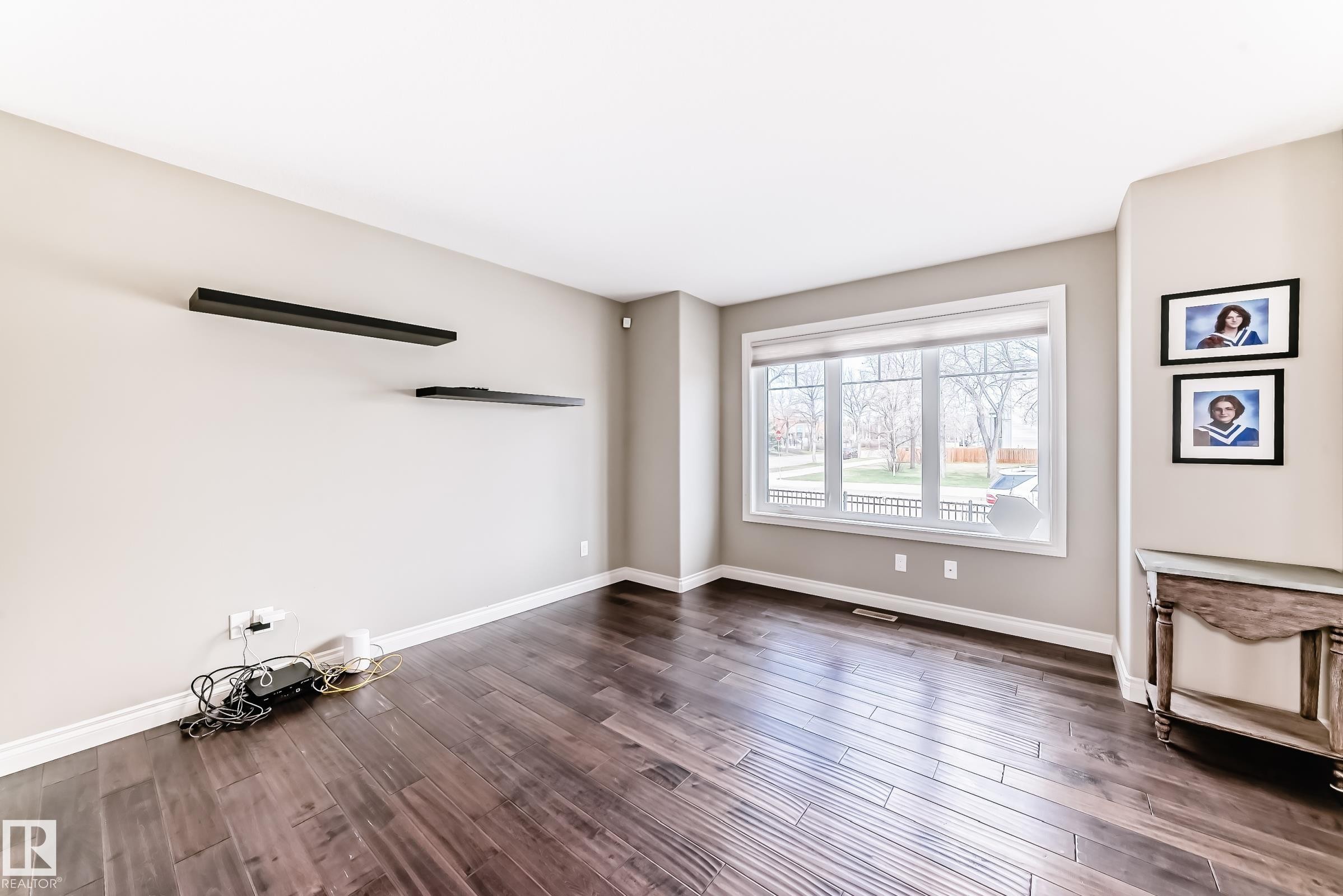 Spacious room featuring wood-finish flooring, light neutral wall paint, and white trim - 10519 114 Avenue, Edmonton, AB - Indoor Photo Showing Other Room