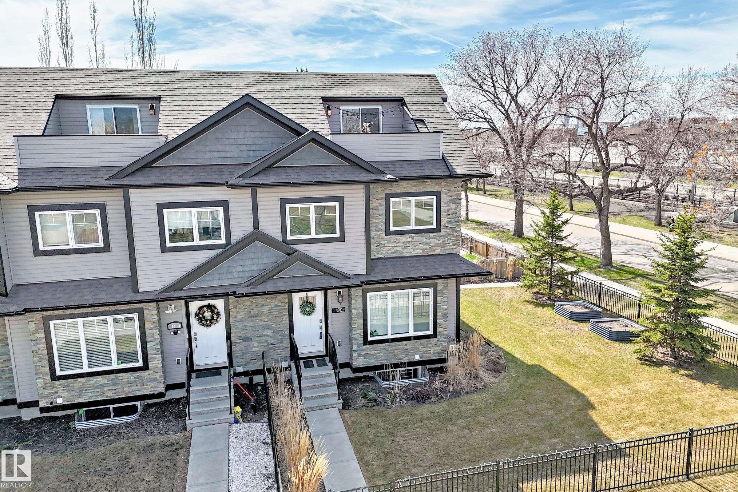 Modern townhome featuring gray siding, stone accents, black trim windows, and a dark shingle roof - 10519 114 Avenue, Edmonton, AB - Outdoor With Facade