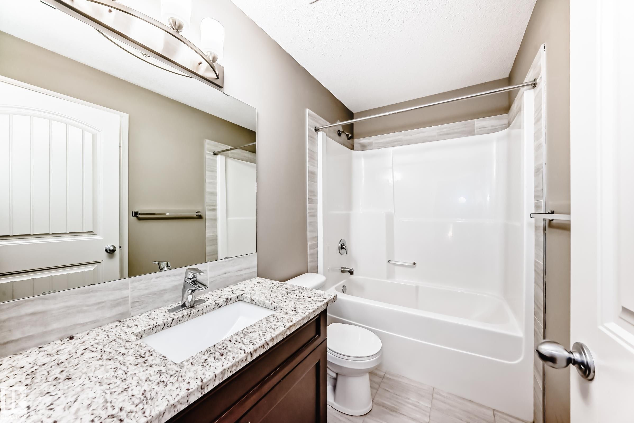 Bathroom featuring a vanity with a white countertop and integrated sink, a dark wood-finish cabinet, and a large wall-mounted mirror - 10519 114 Avenue, Edmonton, AB - Indoor Photo Showing Bathroom