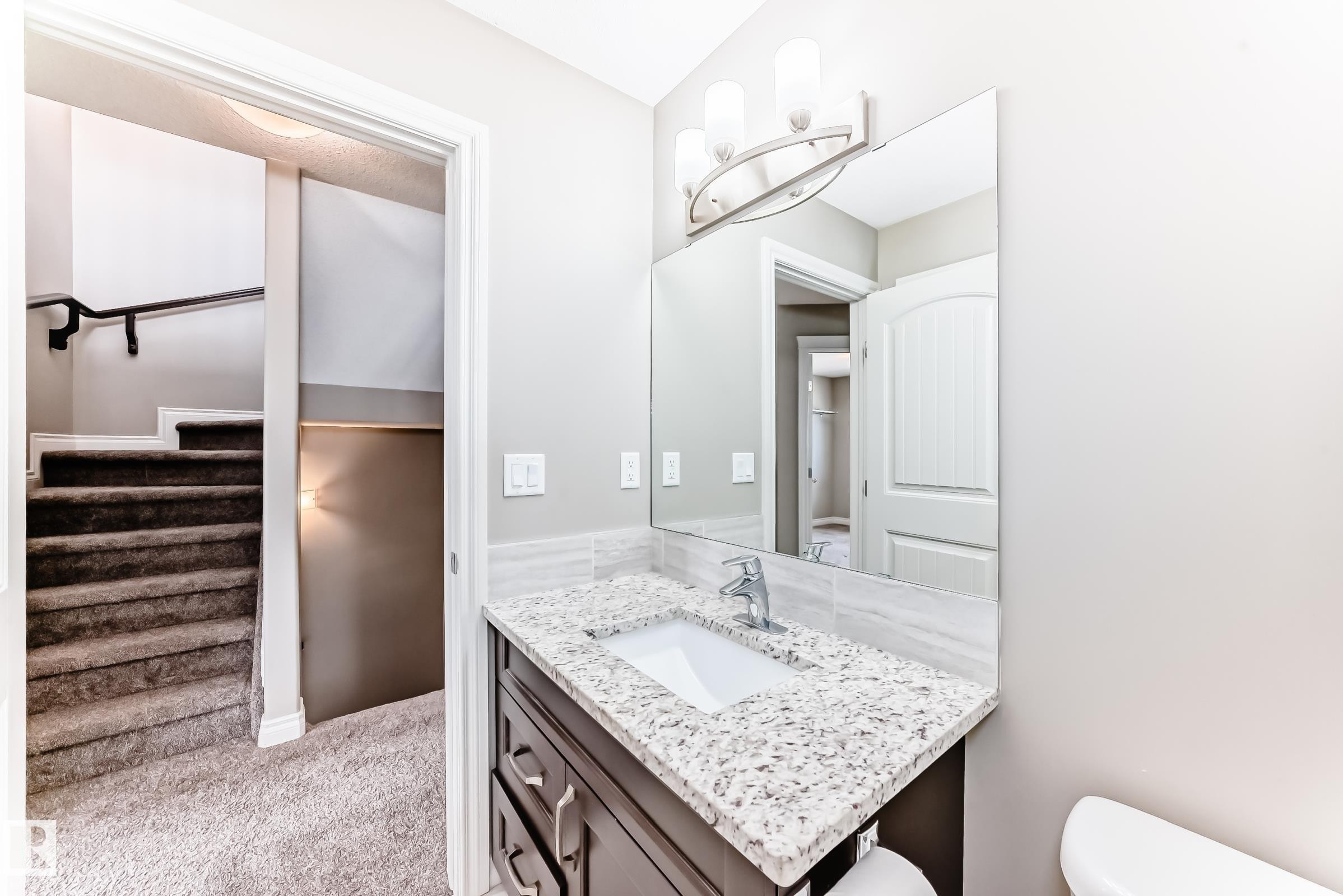 Bathroom vanity featuring a speckled countertop, undermount sink, and dark wood-finish cabinetry - 10519 114 Avenue, Edmonton, AB - Indoor Photo Showing Bathroom