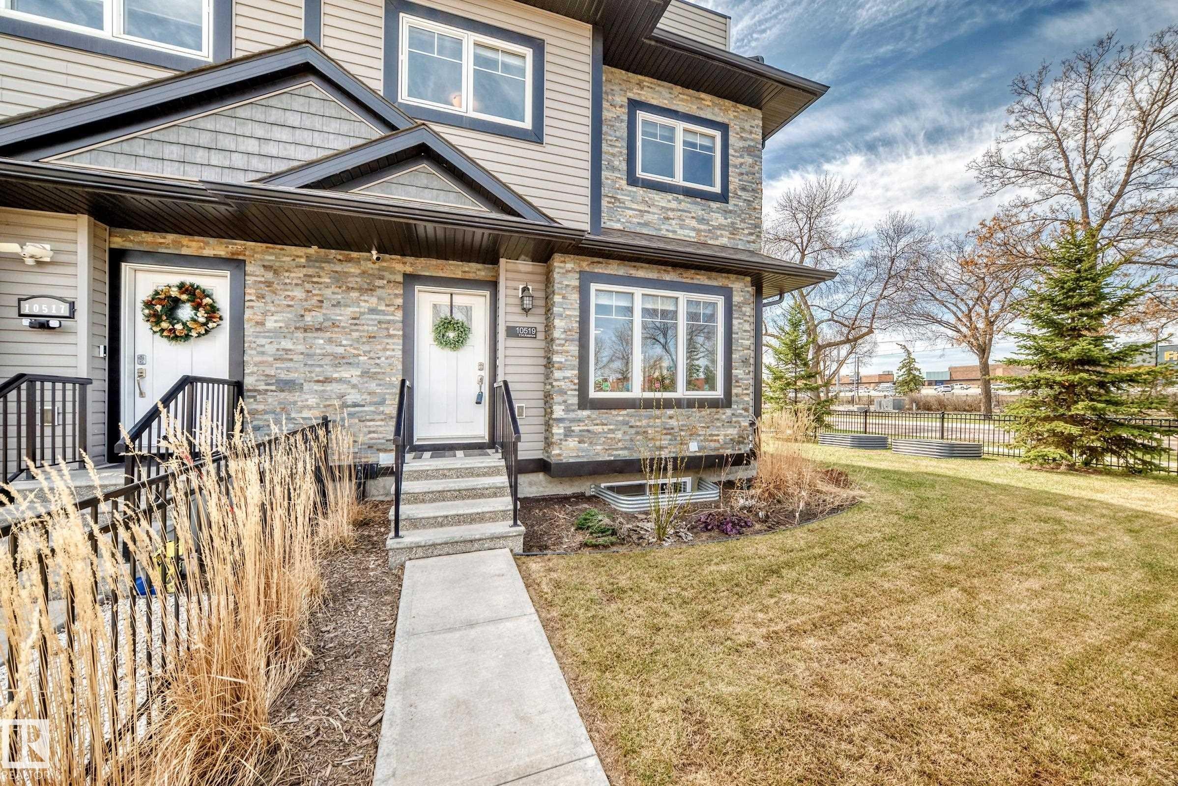 Exterior featuring stacked stone accents, horizontal siding, black trim windows, a concrete walkway, and a landscaped front yard with a mature evergreen - 10519 114 Avenue, Edmonton, AB - Outdoor