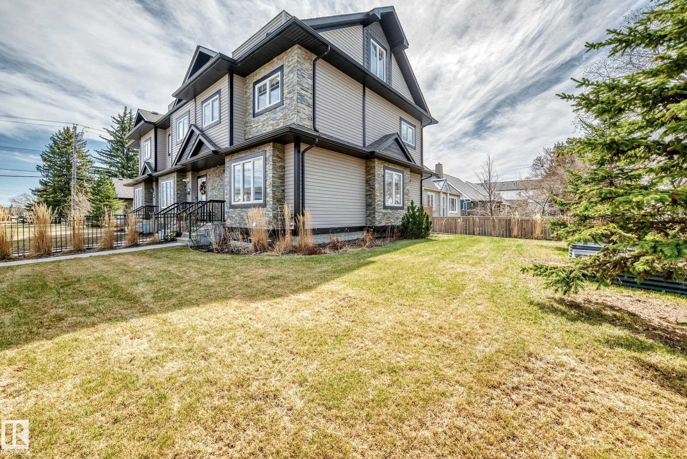 Multi-level townhouse exterior featuring stone veneer accents, light-toned siding, and dark trim - 10519 114 Avenue, Edmonton, AB - Outdoor