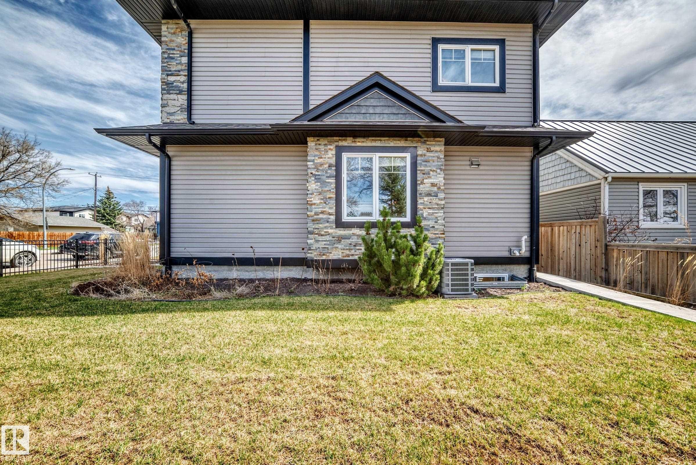 Exterior showcasing light gray horizontal siding, dark gray trim, and stone accents - 10519 114 Avenue, Edmonton, AB - Outdoor