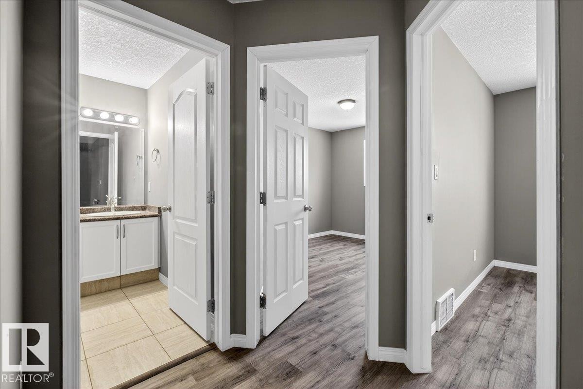 Corridor with a textured ceiling and light wood-style flooring - 150 Acacia Circle, Leduc, AB - Indoor Photo Showing Other Room