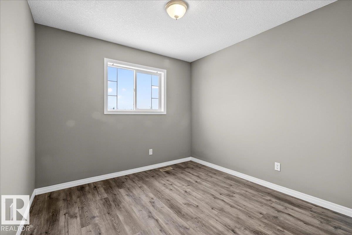 Empty room with a textured ceiling and wood finished floors - 150 Acacia Circle, Leduc, AB - Indoor Photo Showing Other Room