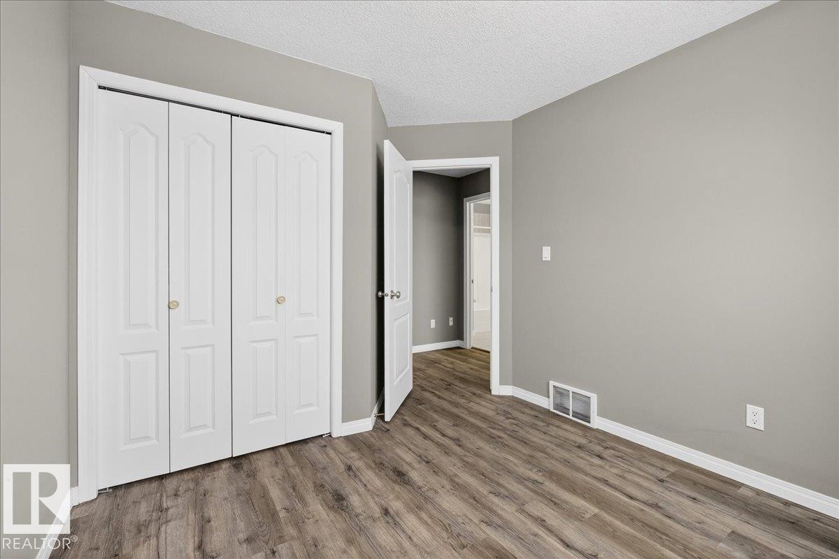 Unfurnished bedroom with a closet, a textured ceiling, and wood finished floors - 150 Acacia Circle, Leduc, AB - Indoor