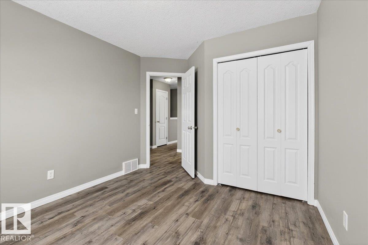 Unfurnished bedroom featuring a textured ceiling, a closet, and wood finished floors - 150 Acacia Circle, Leduc, AB - Indoor