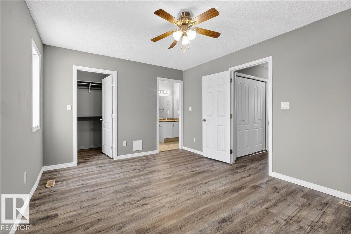 Unfurnished bedroom featuring a textured ceiling, light wood-type flooring, a spacious closet, ceiling fan, and connected bathroom - 150 Acacia Circle, Leduc, AB - Indoor Photo Showing Other Room