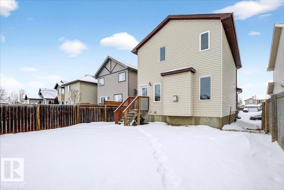 Snow covered rear of property with a fenced backyard and a deck - 150 Acacia Circle, Leduc, AB - Outdoor With Exterior