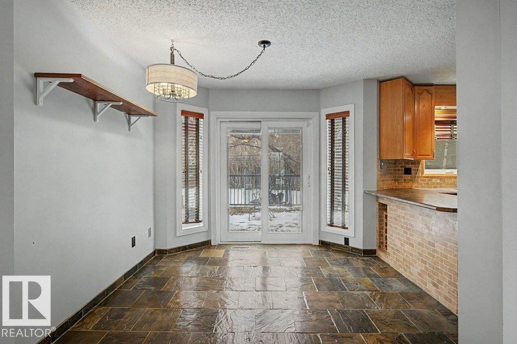 Dining area featuring tiled flooring, a chandelier, and sliding glass doors leading to the outdoors - Edmonton, AB - Indoor Photo Showing Other Room