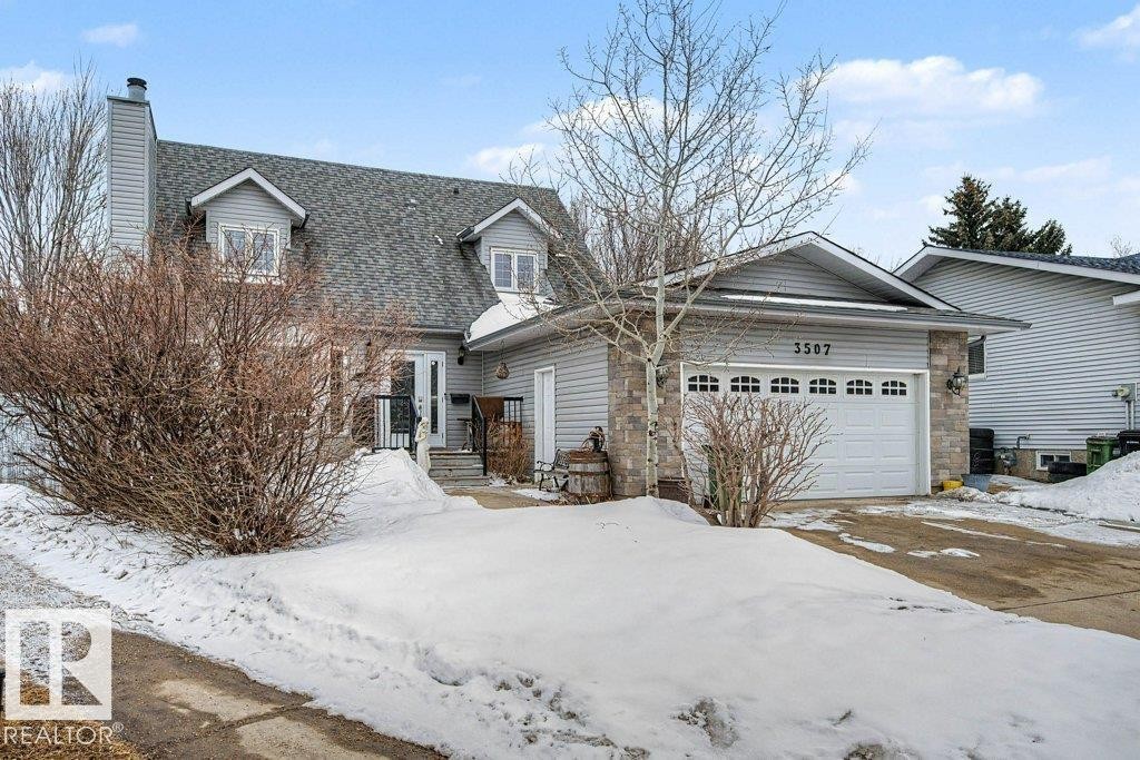 The property features a stone and siding exterior, a front entry with a small porch, and a two-car garage with a windowed door - Edmonton, AB - Outdoor