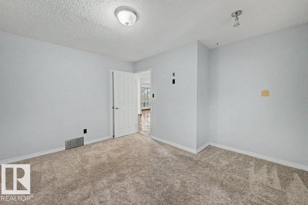 Room featuring light-colored walls, textured carpeting, and a white interior door - Edmonton, AB - Indoor Photo Showing Other Room