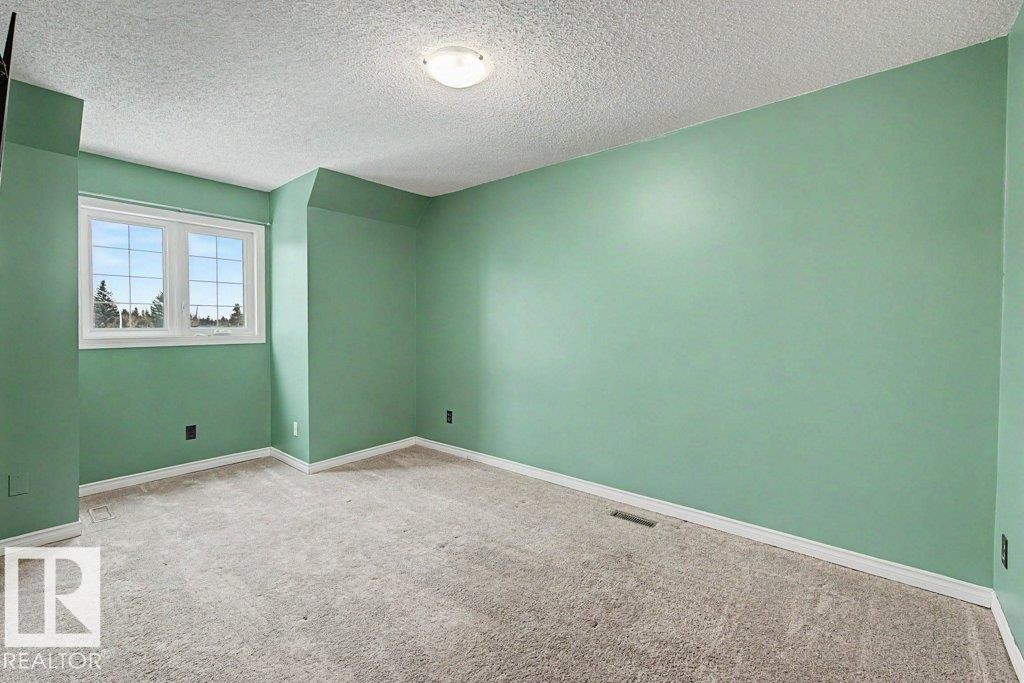 This room features light green walls, a window with views of trees, and carpeted flooring - Edmonton, AB - Indoor Photo Showing Other Room