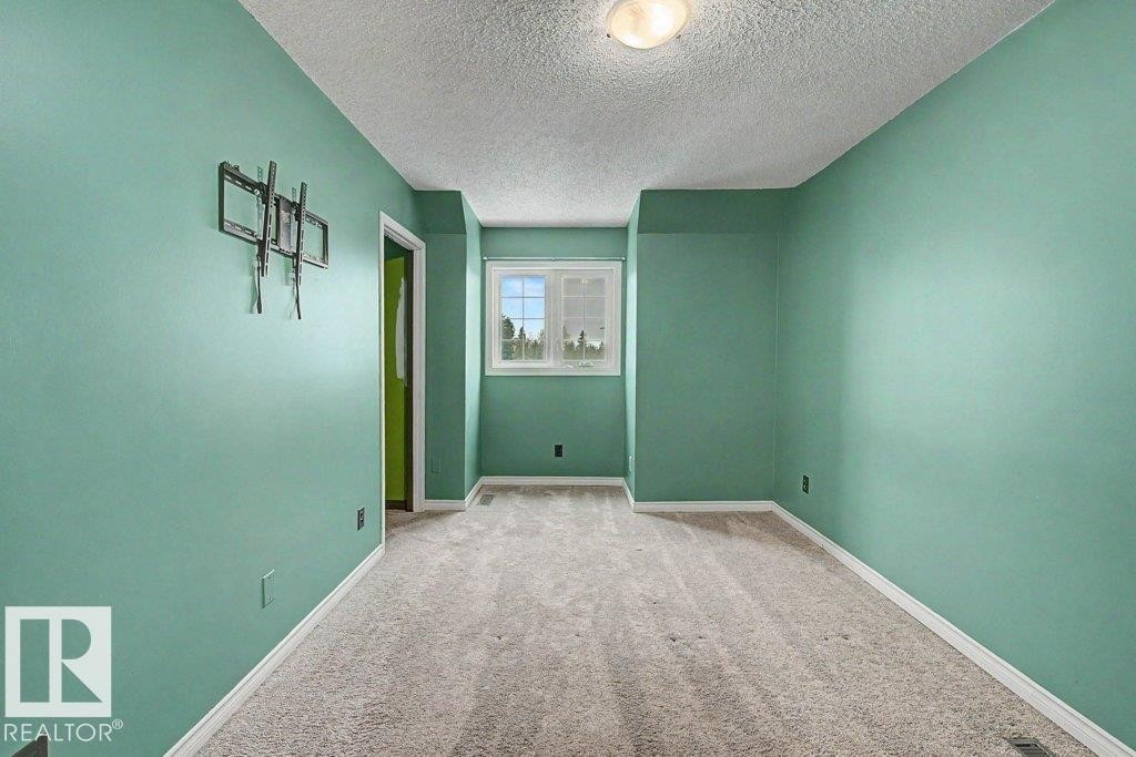 This room features light-colored carpet, a window, and a door frame - Edmonton, AB - Indoor Photo Showing Other Room