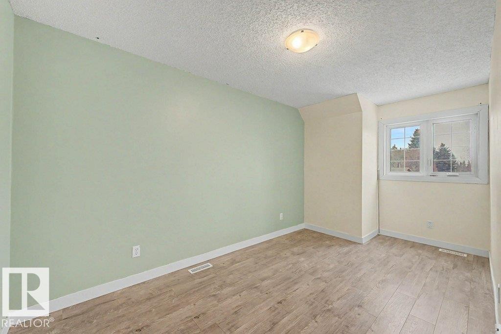 This room features wood-look flooring, light-colored walls, and a window providing natural light - Edmonton, AB - Indoor Photo Showing Other Room