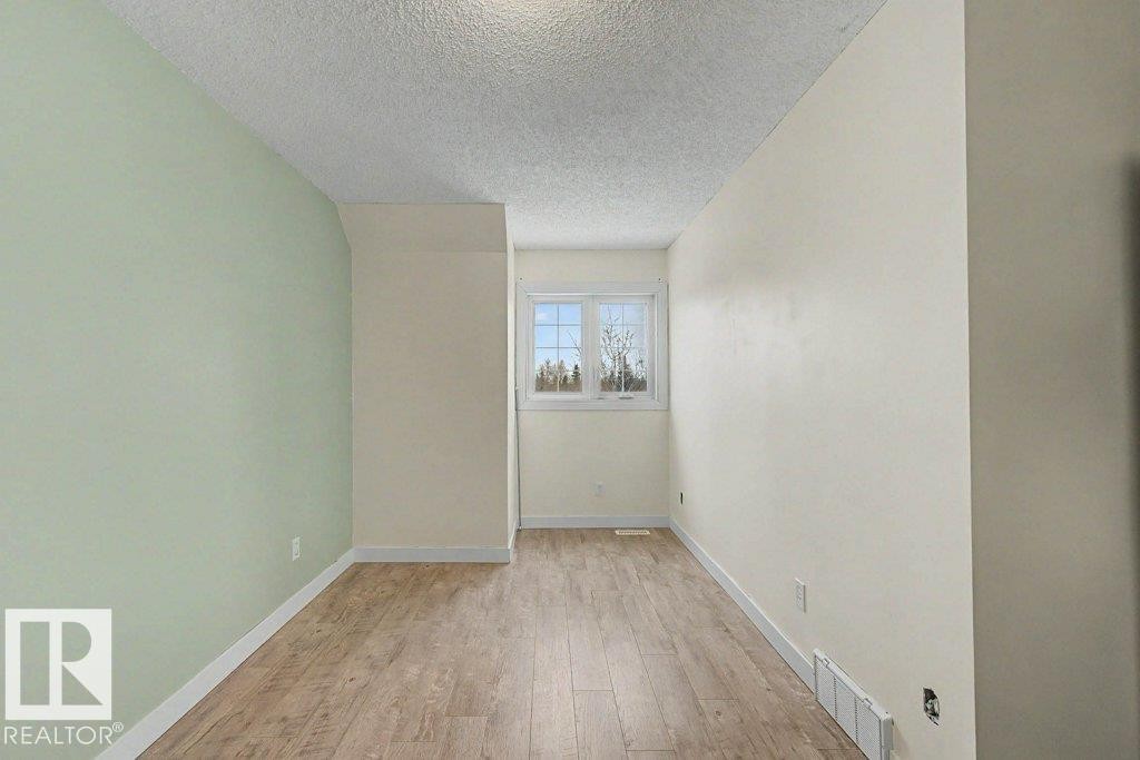 This interior space features light-toned flooring, a window providing natural light, and walls painted in contrasting light green and off-white colors - Edmonton, AB - Indoor Photo Showing Other Room