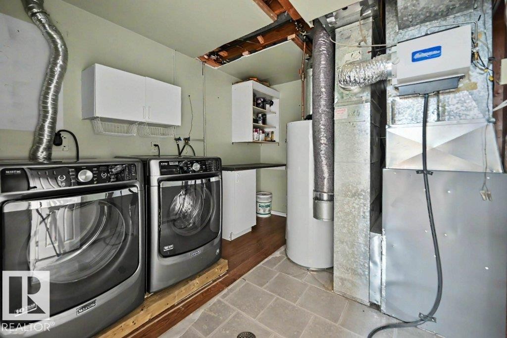 The property includes a dedicated laundry area with white cabinetry, a built-in countertop, and a water heater - Edmonton, AB - Indoor Photo Showing Laundry Room