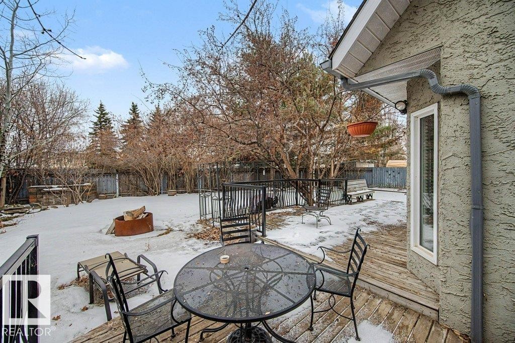 The property features a spacious rear yard with mature trees, a wooden fence, and a patio deck - Edmonton, AB - Outdoor With Deck Patio Veranda