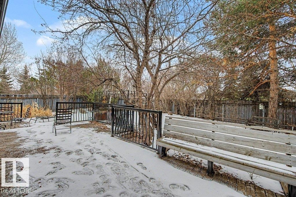 The property features a spacious deck area with metal railings, surrounded by mature trees and a wooden fence - Edmonton, AB - Outdoor