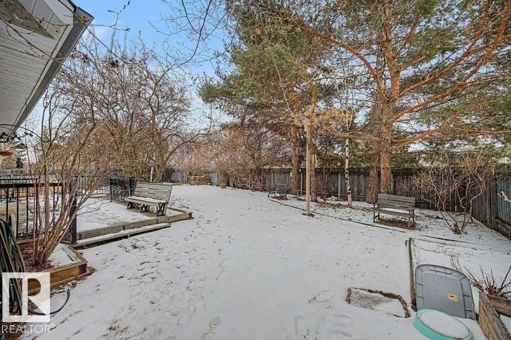 The property features a spacious yard with mature trees and a wooden fence - Edmonton, AB - Outdoor