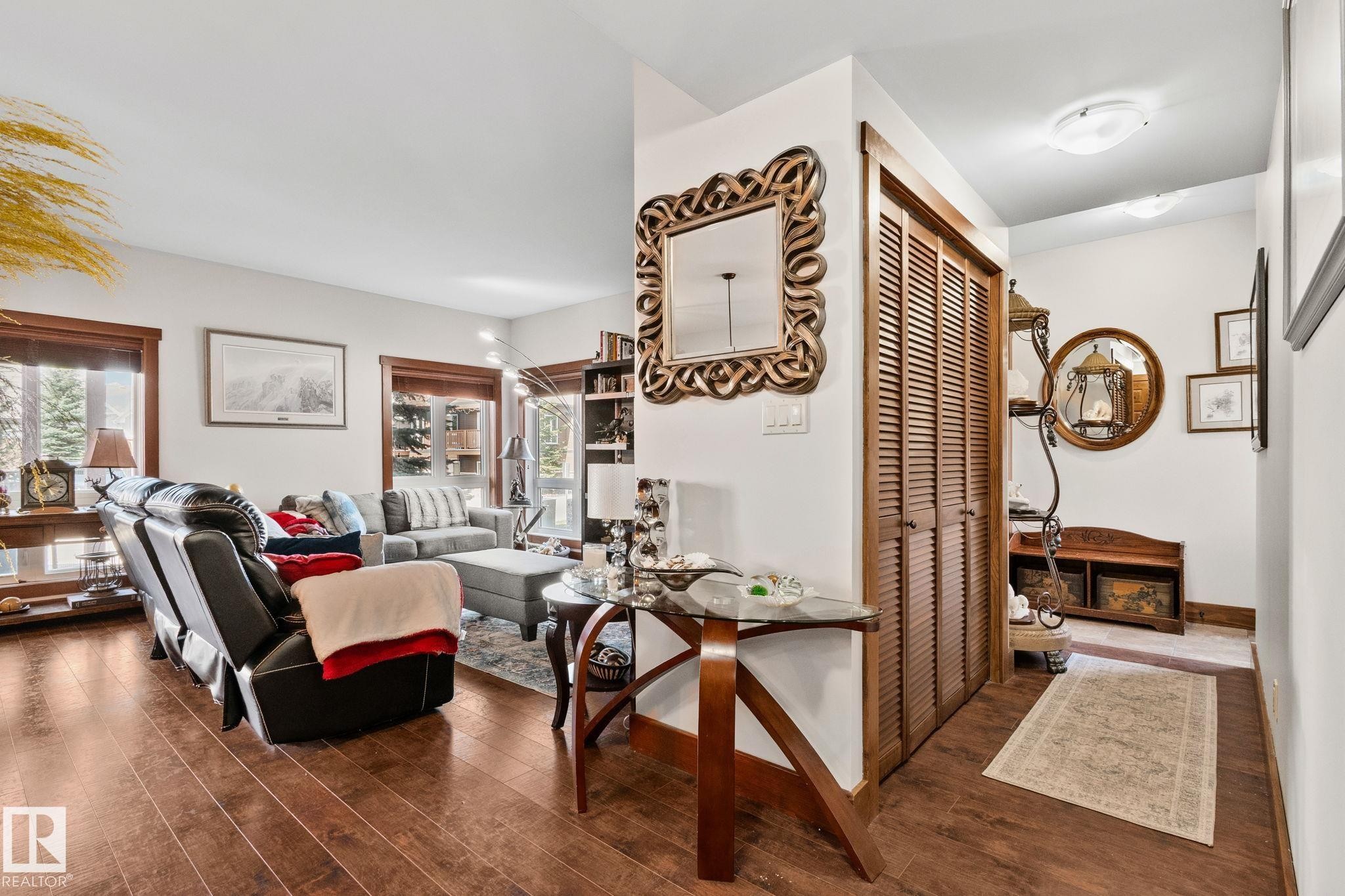 Laminate wood-finish flooring extending into the living area, featuring white walls, and wood-trimmed windows providing natural light - 2201 Graybriar Green, Stony Plain, AB - Indoor Photo Showing Other Room