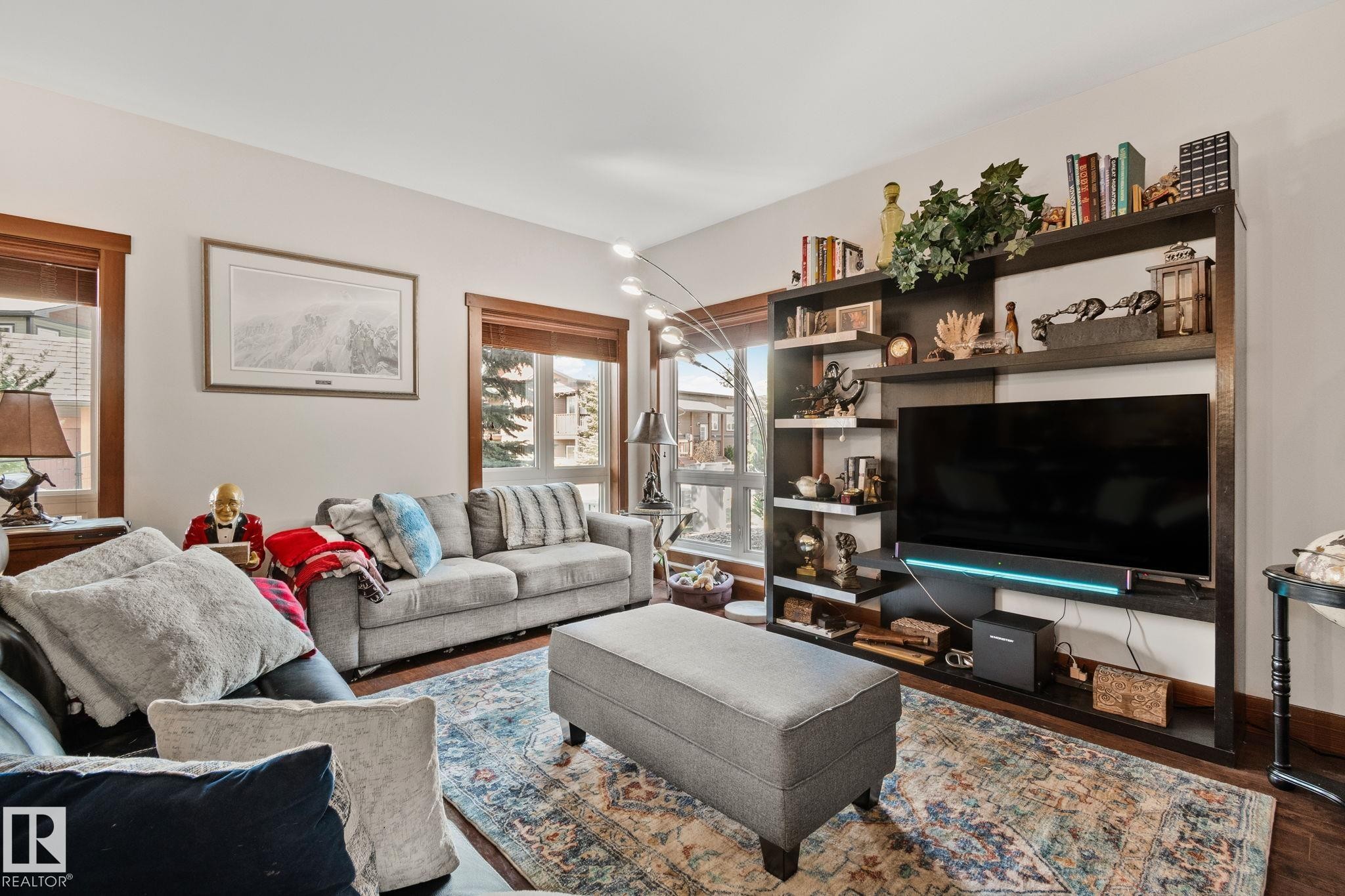 Living area featuring wood-finish flooring, light-toned walls, and multiple windows with wood trim - 2201 Graybriar Green, Stony Plain, AB - Indoor Photo Showing Living Room