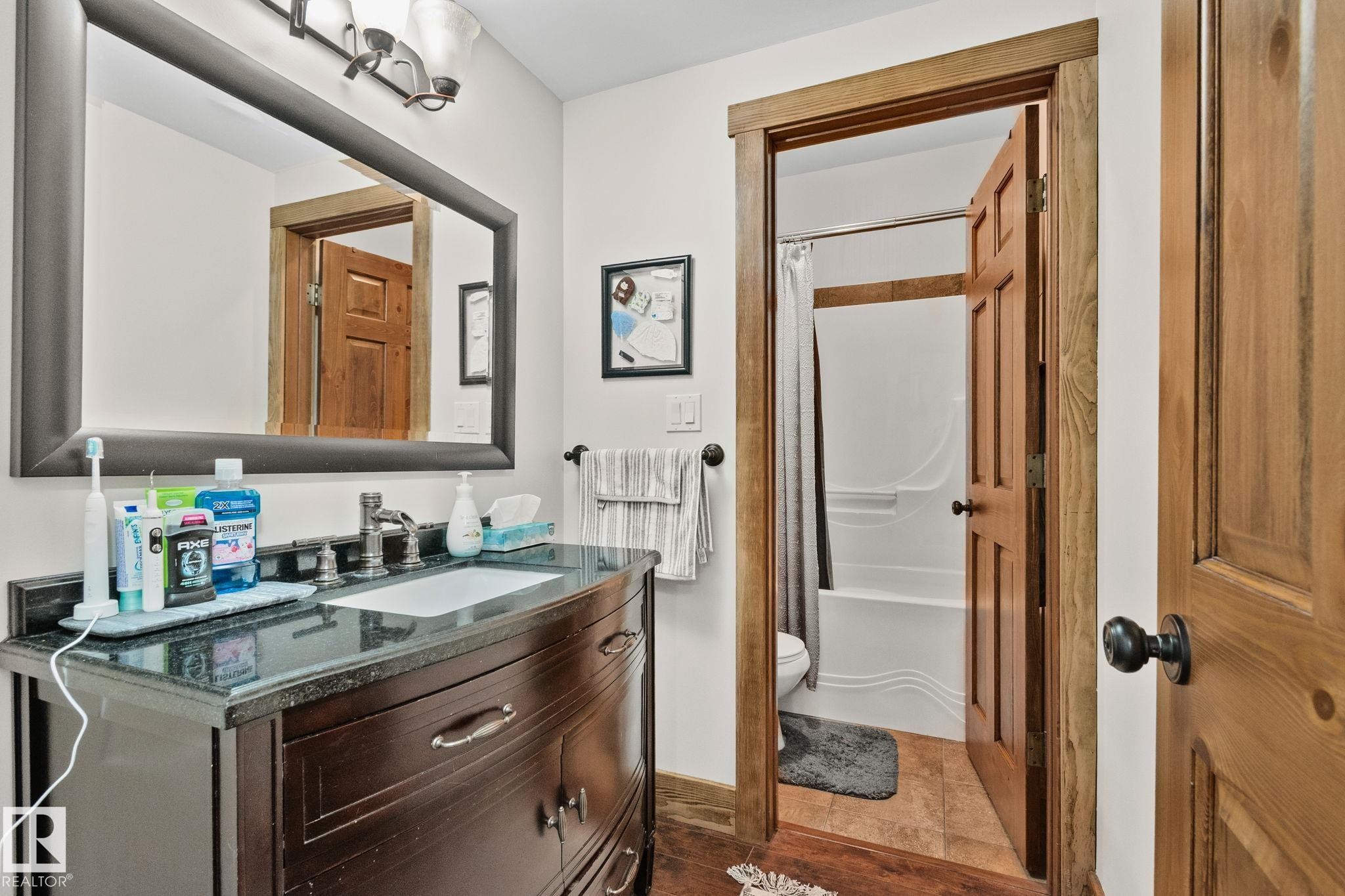 Bathroom vanity featuring a dark wood finish, a black countertop, and an undermount sink with a chrome faucet - 2201 Graybriar Green, Stony Plain, AB - Indoor Photo Showing Bathroom