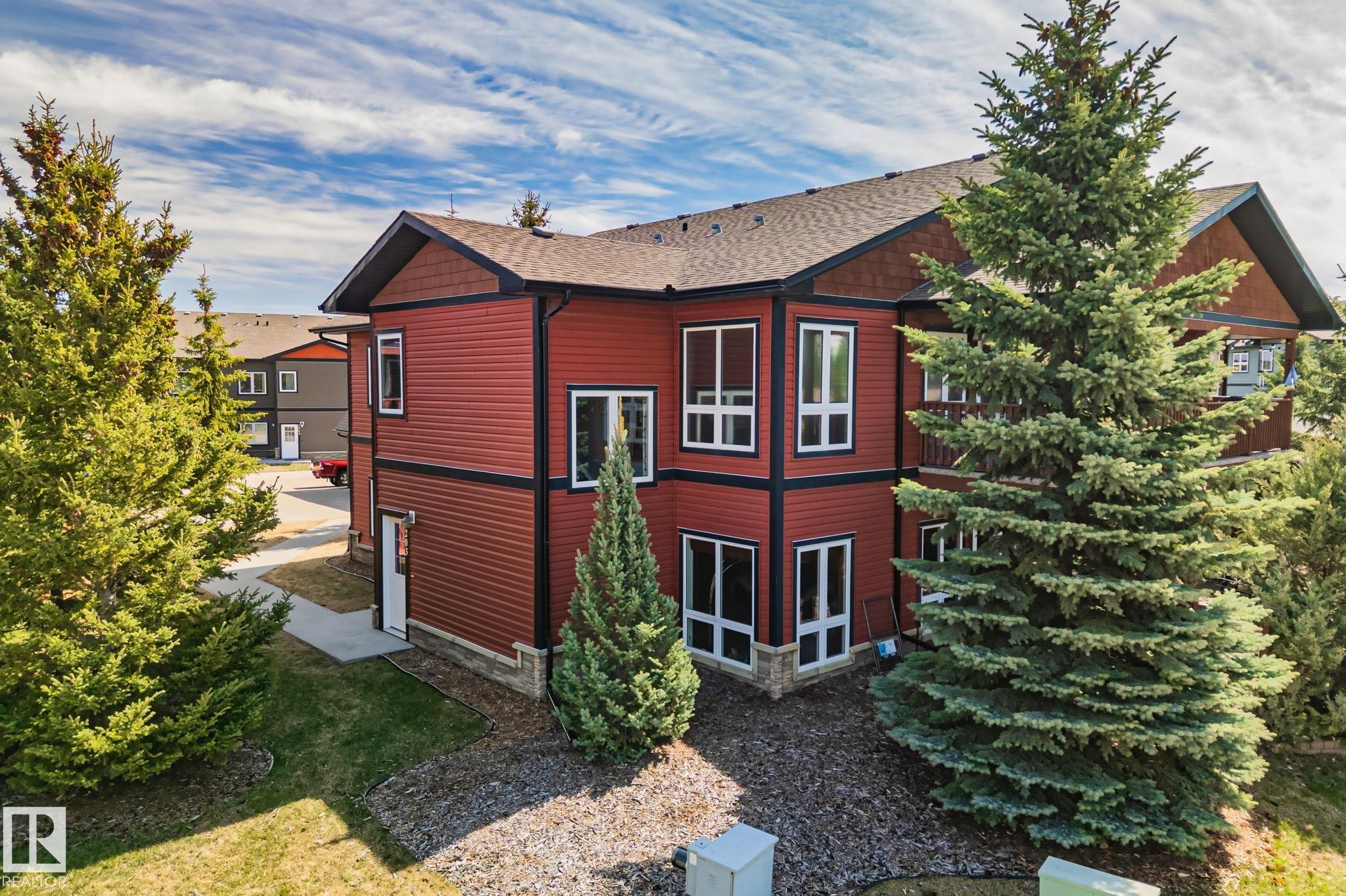 Two-story exterior featuring red siding with dark trim, multiple large windows, and a prominent balcony - 2201 Graybriar Green, Stony Plain, AB - Outdoor