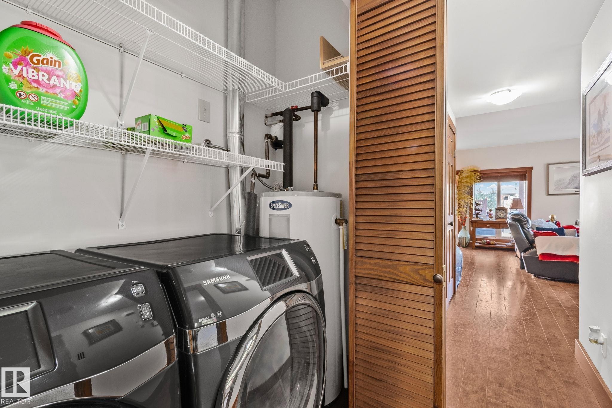 Dedicated utility closet with a water heater, wire shelving, and wood-finish bifold doors - 2201 Graybriar Green, Stony Plain, AB - Indoor Photo Showing Laundry Room