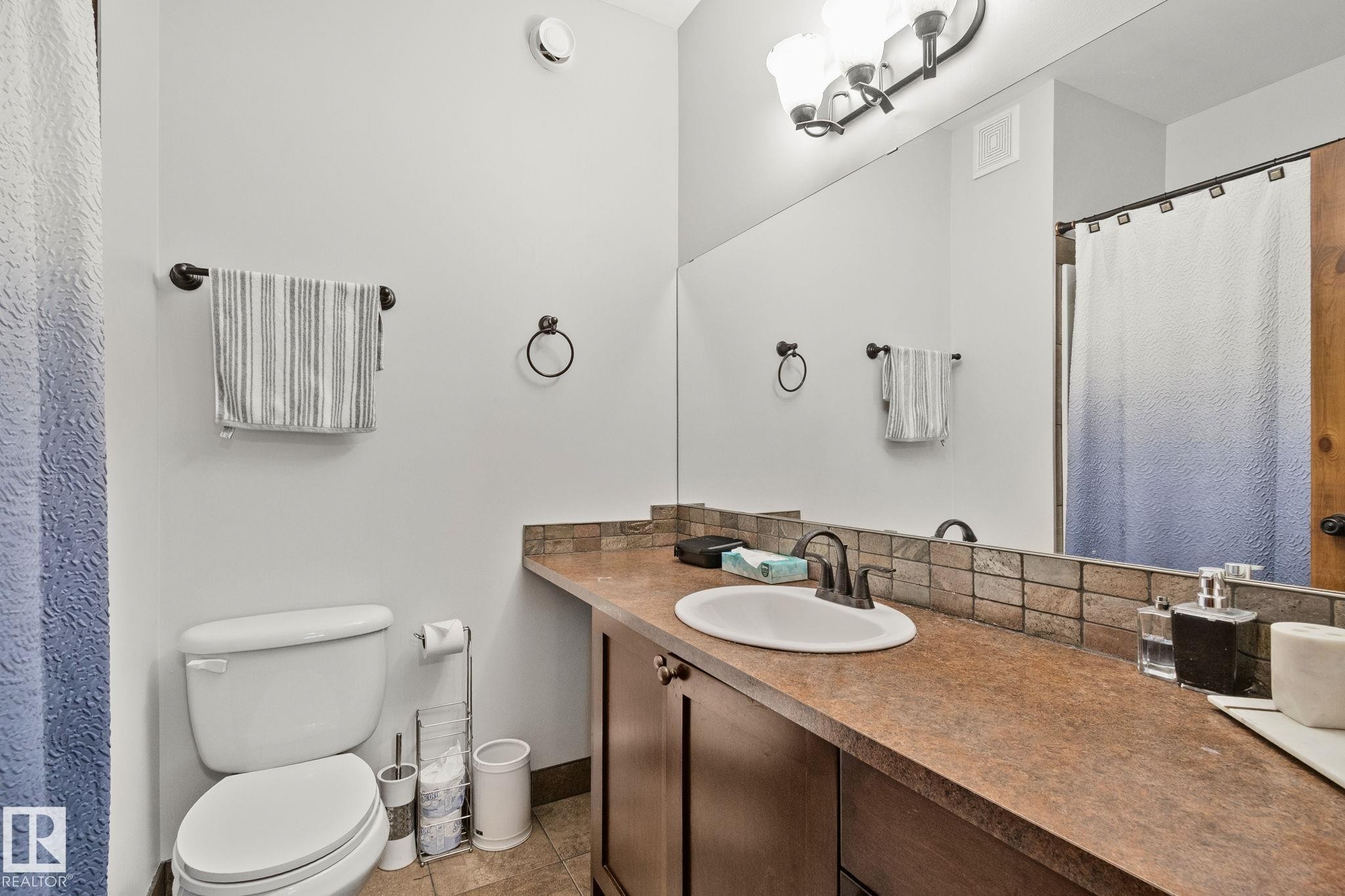 Bathroom featuring an integrated sink, dark wood-finish vanity, and an extensive mirror - 2201 Graybriar Green, Stony Plain, AB - Indoor Photo Showing Bathroom