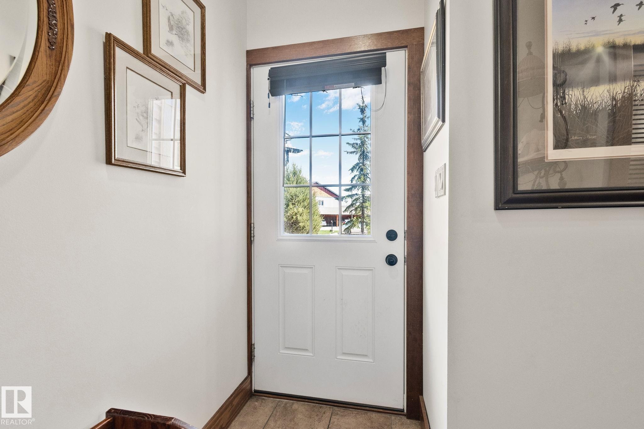 White paneled entry door with grid-patterned glass, dark hardware, and wood-finish trim - 2201 Graybriar Green, Stony Plain, AB - Indoor Photo Showing Other Room