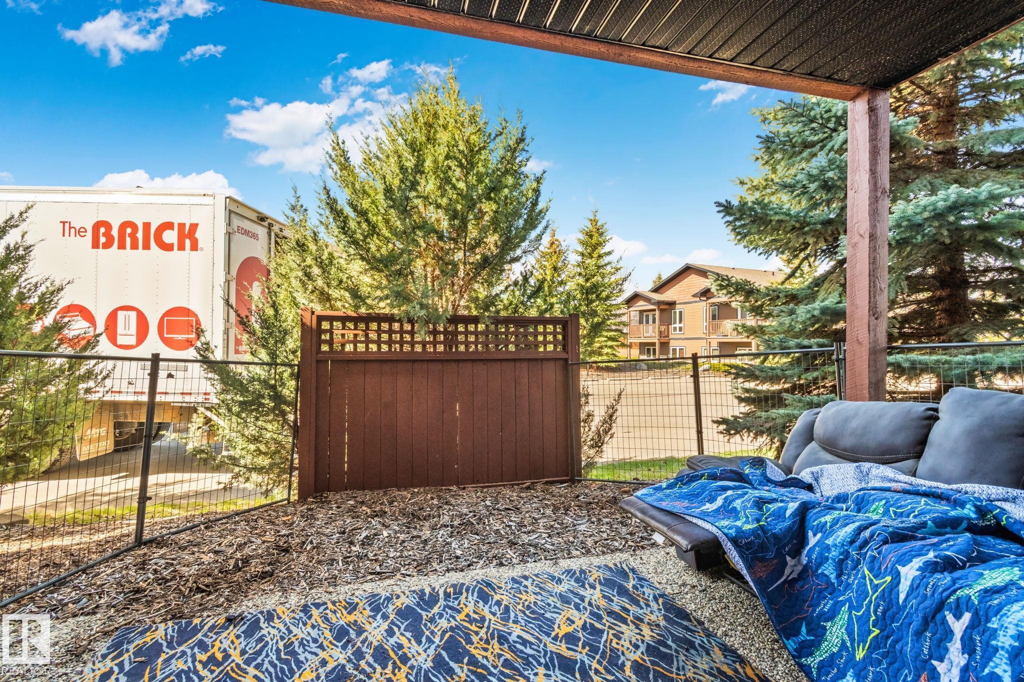 Covered patio featuring a slatted ceiling, wood support beams, and a decorative privacy fence - 2201 Graybriar Green, Stony Plain, AB - Outdoor With Deck Patio Veranda