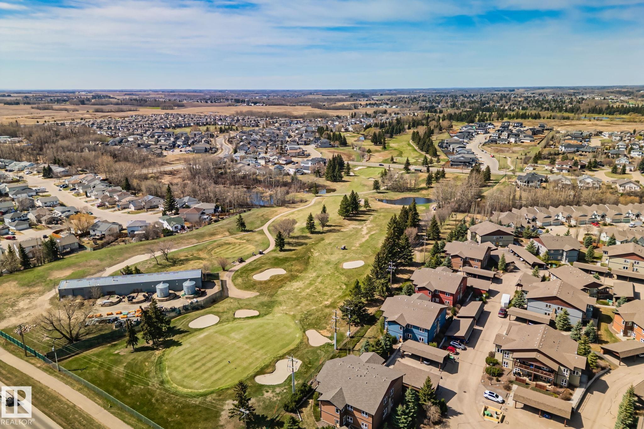 Aerial perspective showcasing a residential area with a golf course, expansive green spaces, and dense tree coverage - 2201 Graybriar Green, Stony Plain, AB - Outdoor With View