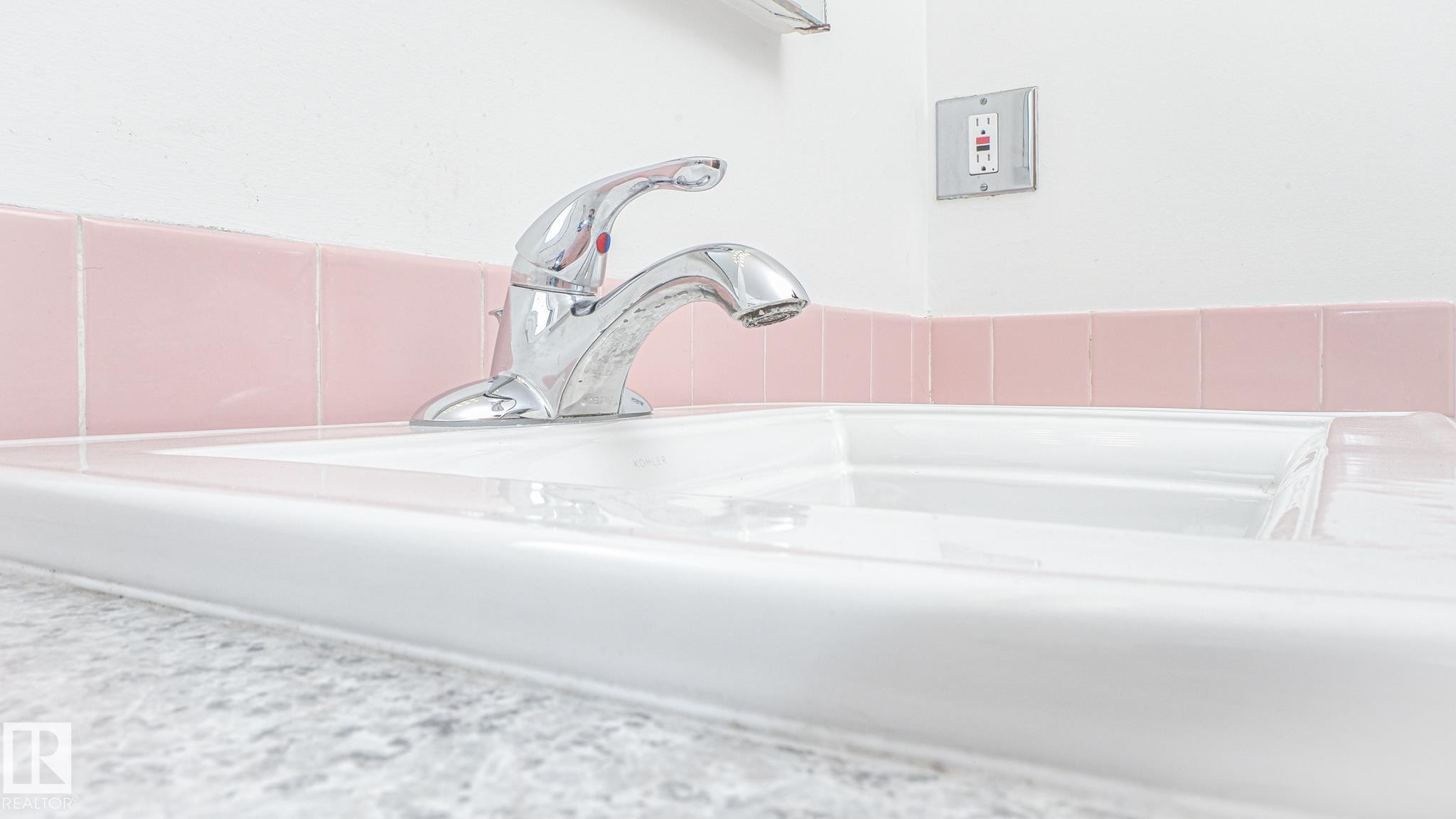 White ceramic sink with a chrome faucet, set against a countertop with a subtle textured finish - 11131 52 Street, Edmonton, AB - Indoor Photo Showing Bathroom