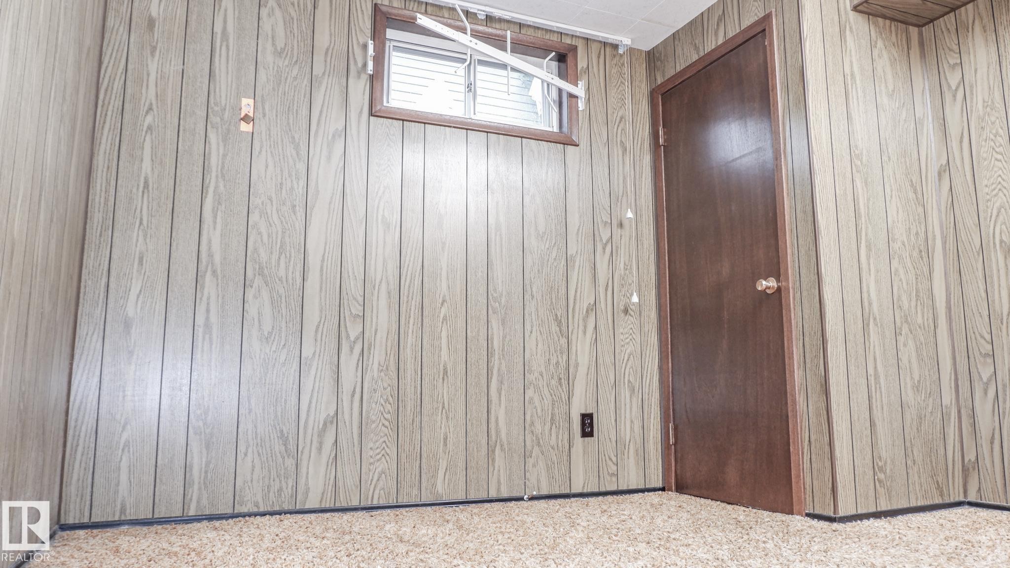 Paneled walls with wood-finish texture, presenting a window with horizontal blinds - 11131 52 Street, Edmonton, AB - Indoor Photo Showing Other Room