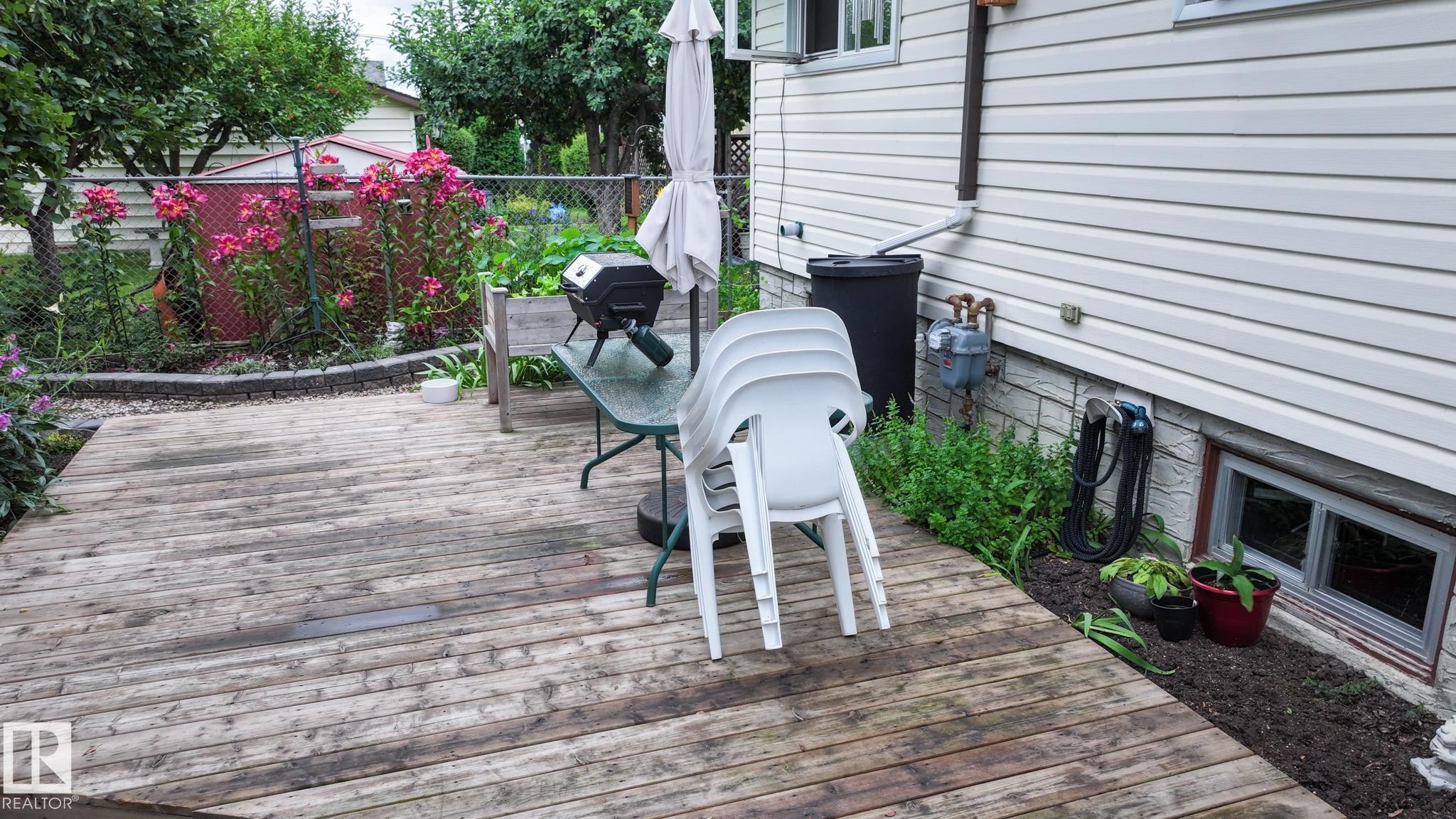 Spacious wood-finish deck bordered by a planting bed - 11131 52 Street, Edmonton, AB - Outdoor With Deck Patio Veranda With Exterior