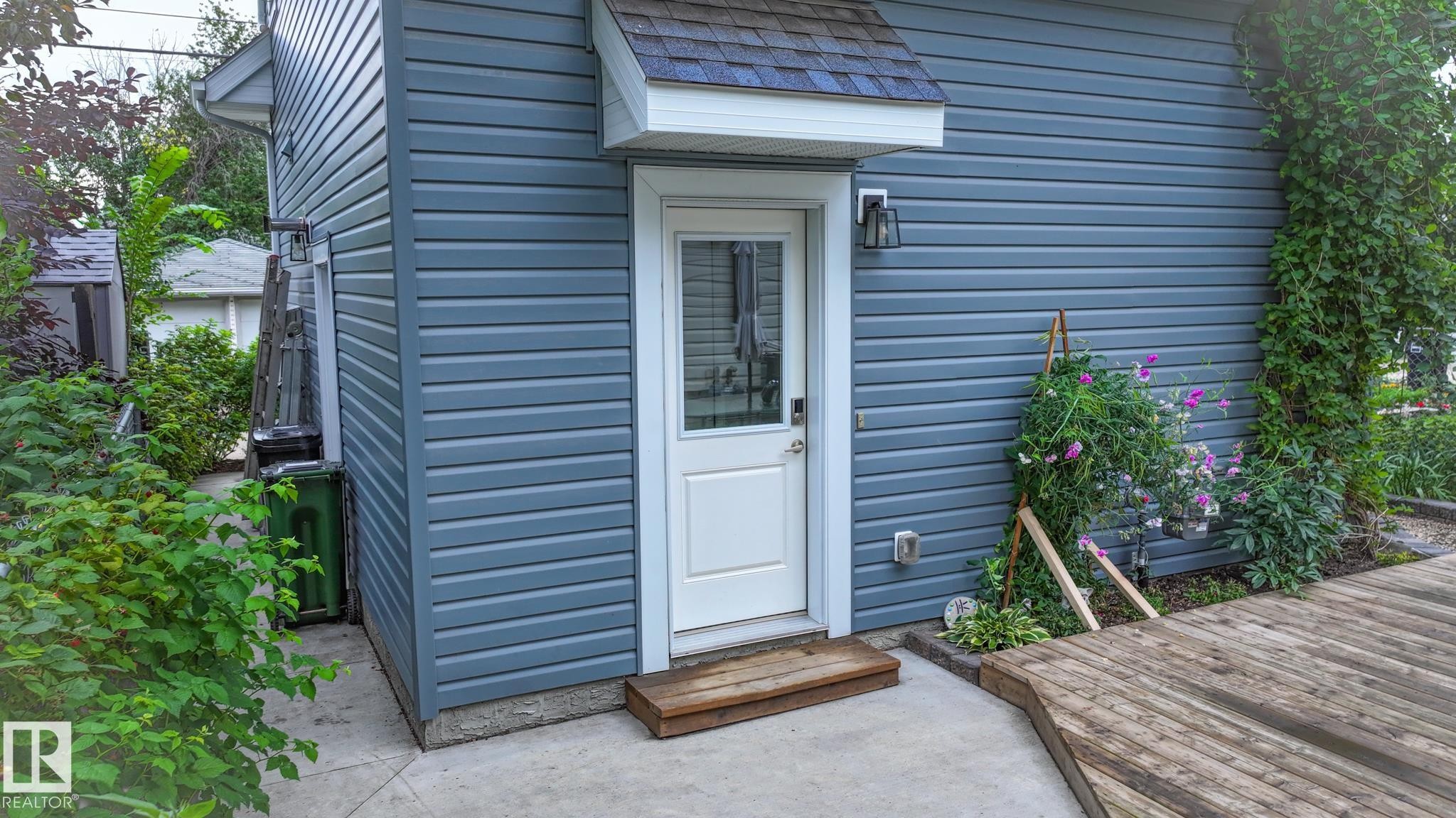 Exterior siding in a slate blue finish with white trim, featuring a white door with glass panels - 11131 52 Street, Edmonton, AB - Outdoor