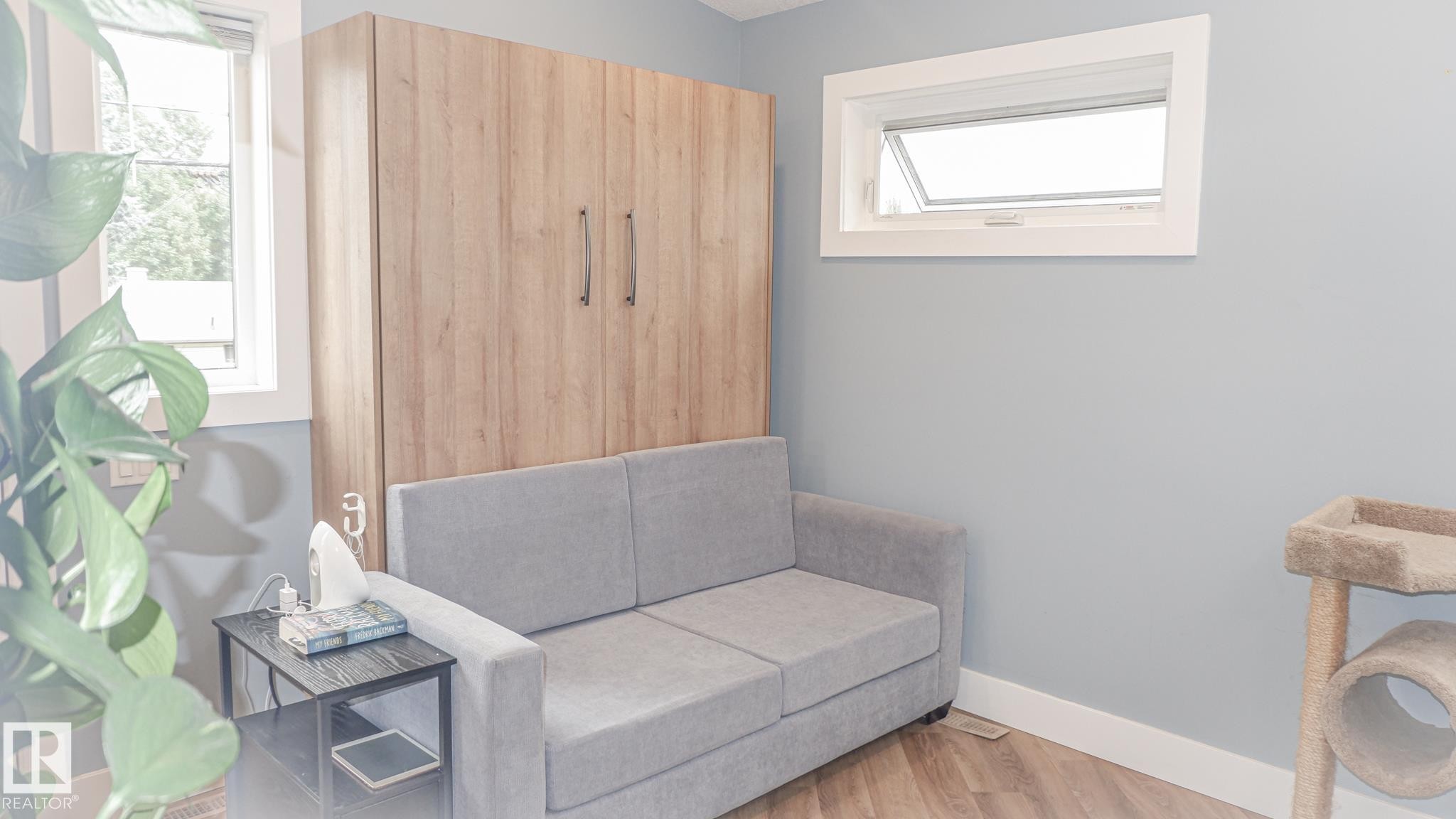 Room featuring a light wood-finish wall unit, two windows with white trim, and light blue wall paint - 11131 52 Street, Edmonton, AB - Indoor