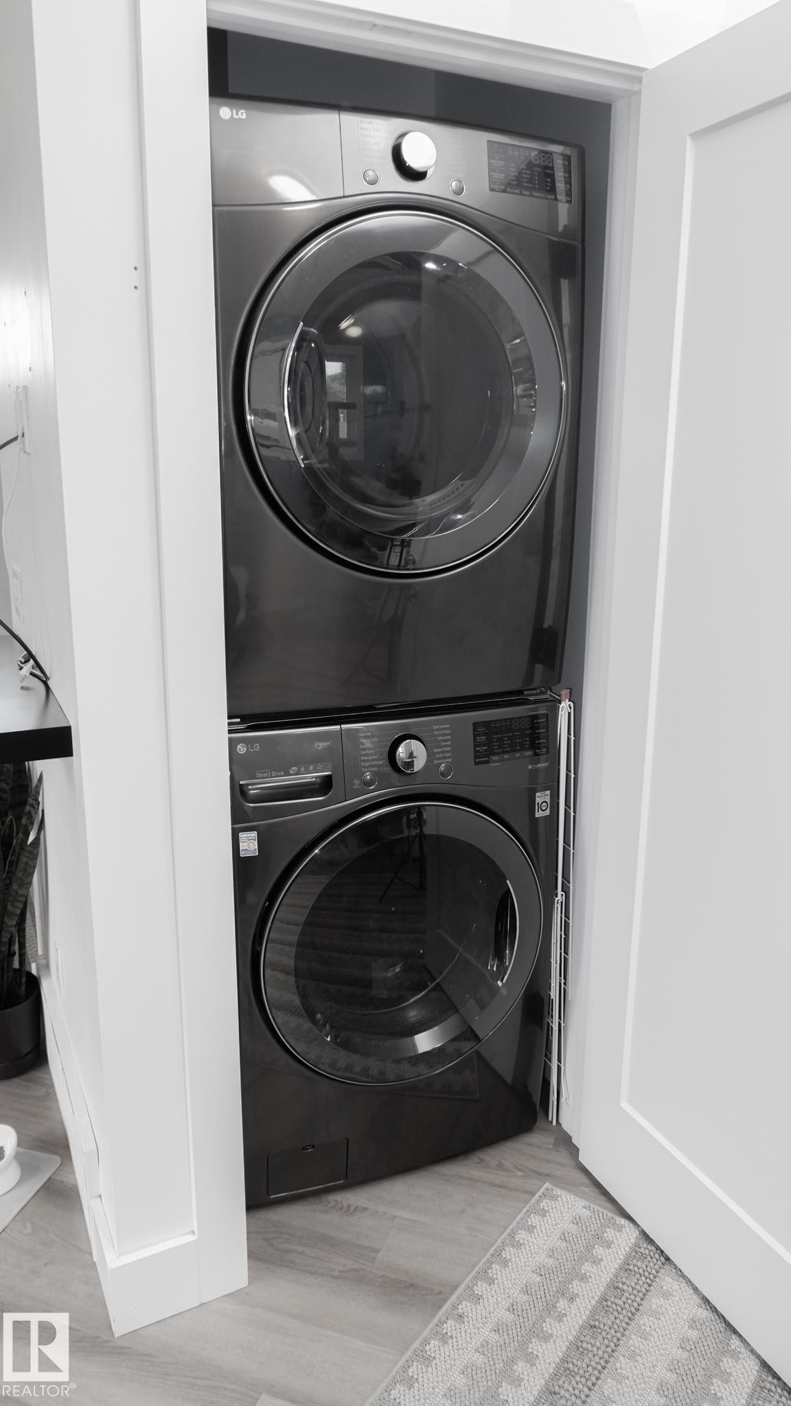 Stacked laundry appliances within a dedicated closet space, featuring a dark finish and front-loading design - 11131 52 Street, Edmonton, AB - Indoor Photo Showing Laundry Room