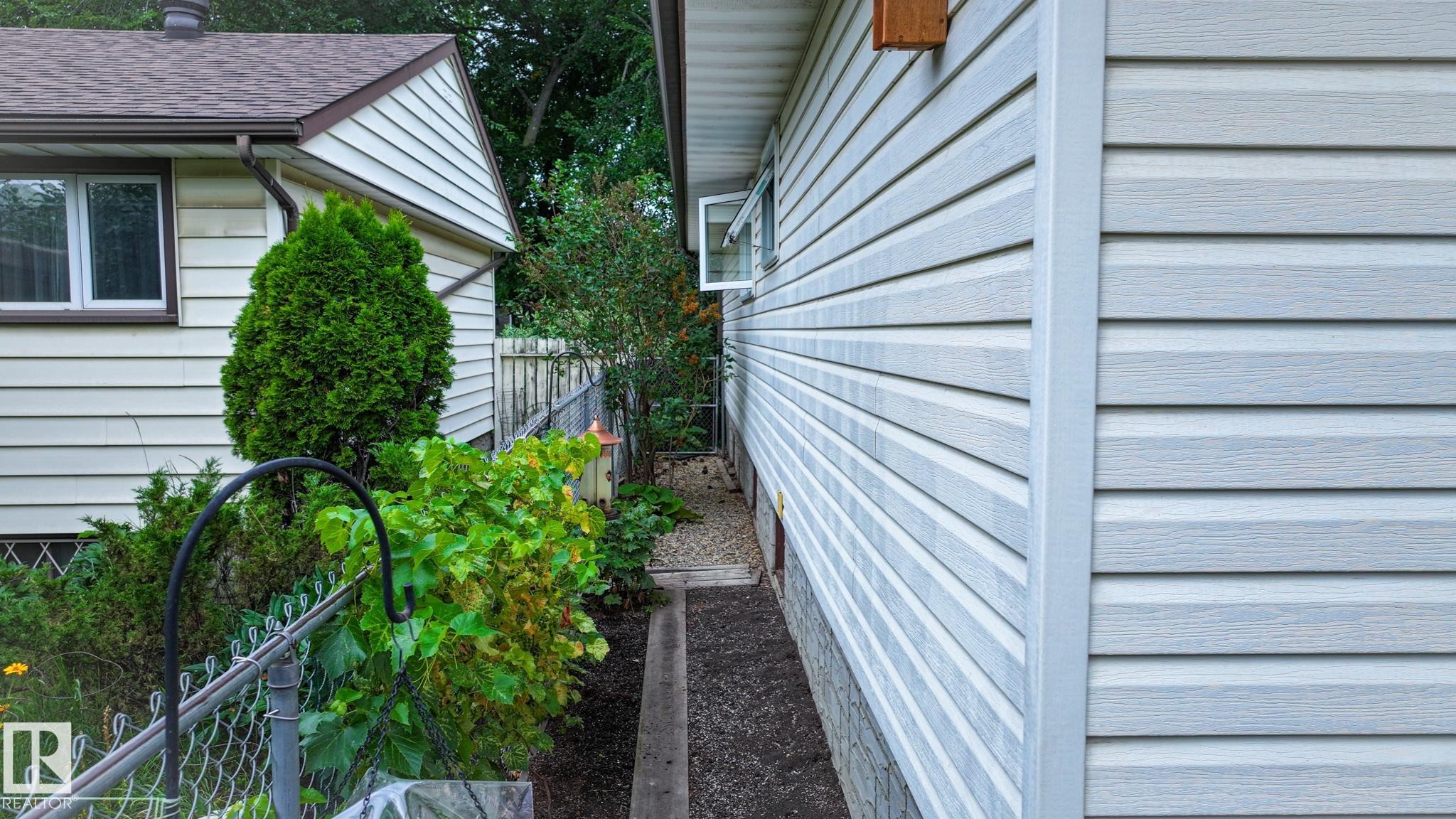 Light-colored horizontal siding facade with a window and foundation stonework - 11131 52 Street, Edmonton, AB - Outdoor With Exterior