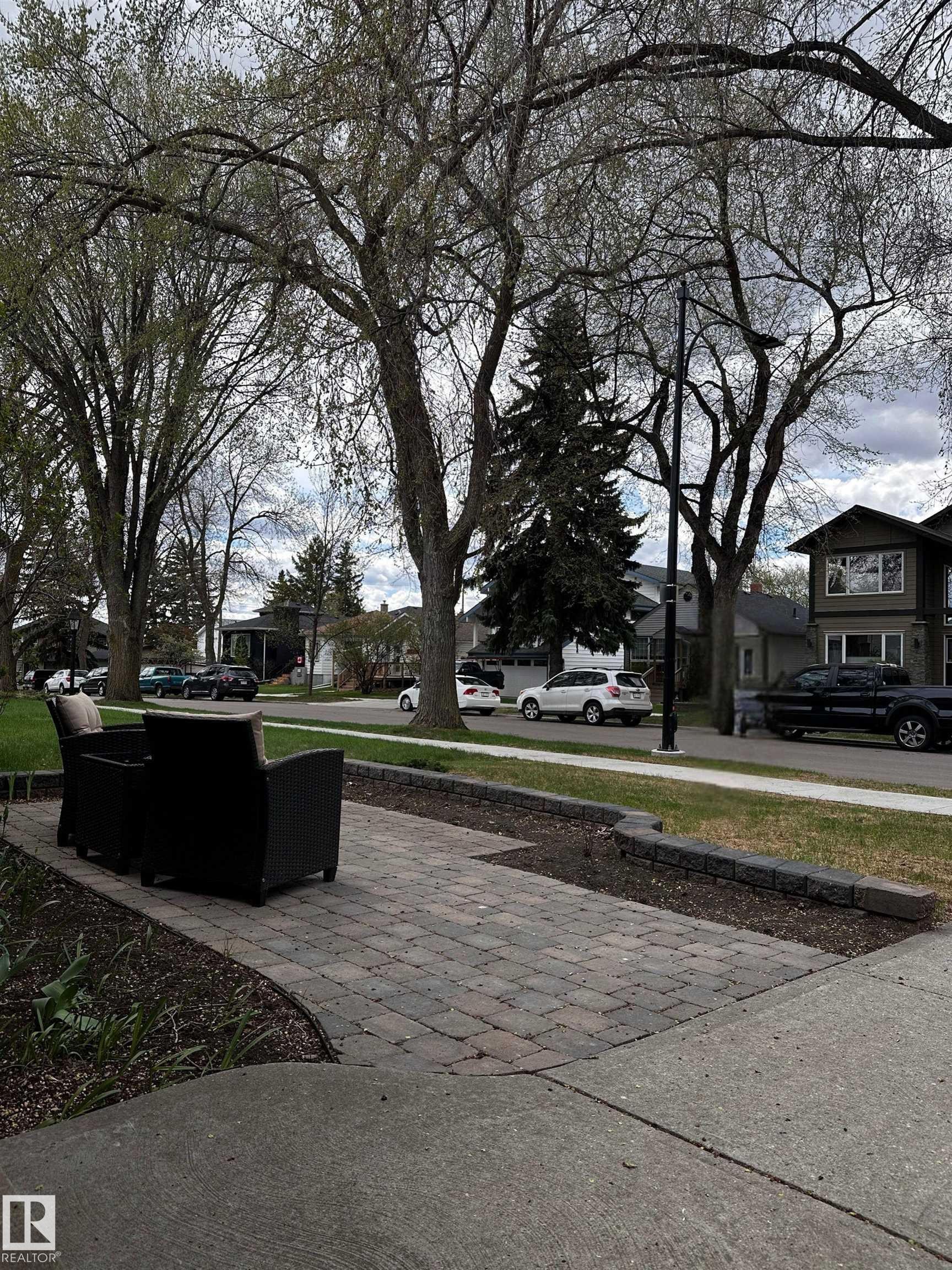 Paver patio area with a stone retaining wall and mature trees - 11131 52 Street, Edmonton, AB - Outdoor