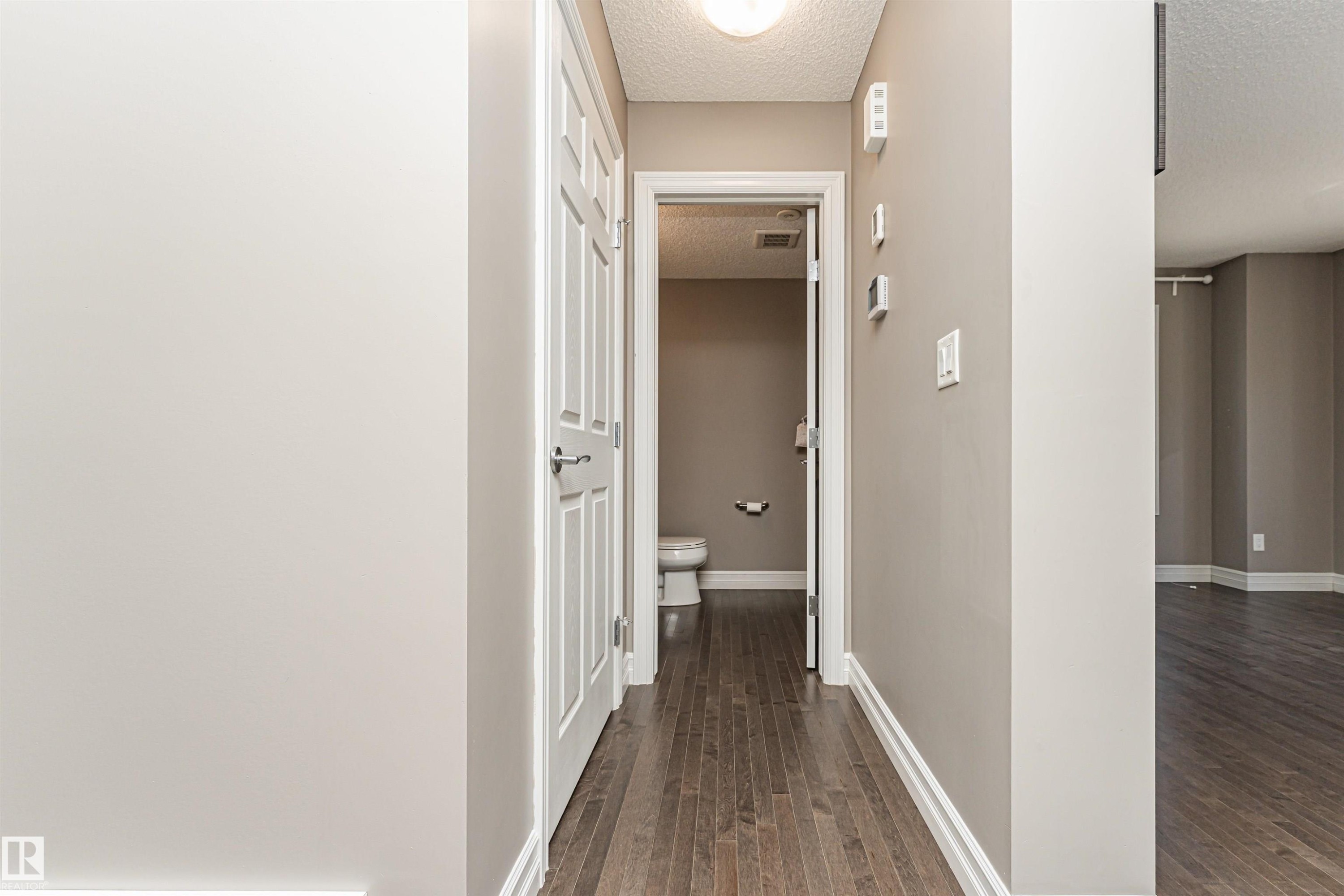 Hallway featuring wood-finish flooring, white trim, and a built-in overhead light fixture - #110 3625 144 Av Nw, Edmonton, AB - Indoor Photo Showing Other Room