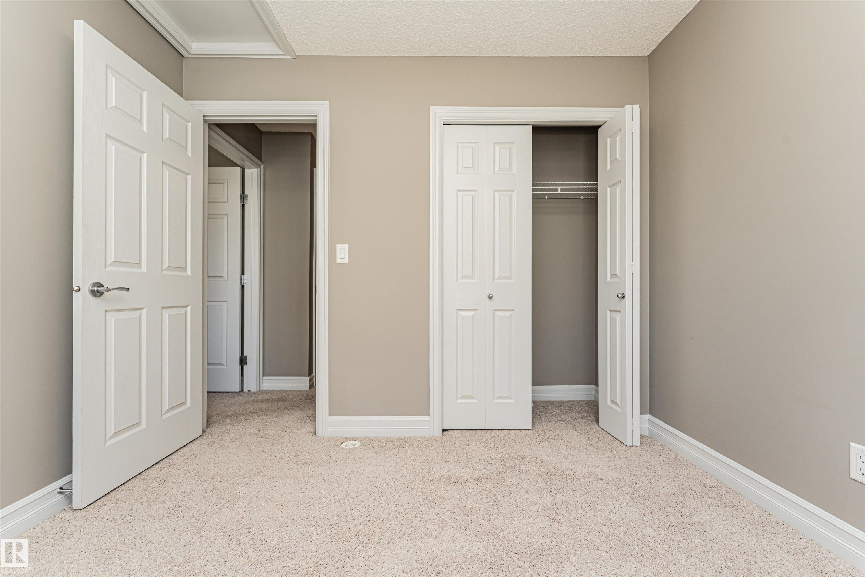 Neutral tone wall finishes, white trim, and light-toned carpeting define this interior space - #110 3625 144 Av Nw, Edmonton, AB - Indoor Photo Showing Other Room